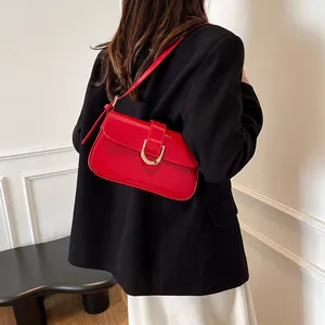 Elegante rode lakleren tas voor onder de arm met gouden U-gesp op een zwarte blazer