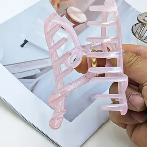 Nahaufnahme einer großen, durchscheinenden rosa Haarspange in Herzform in der Hand