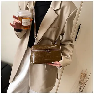 Brown crocodile pattern box bag held by model in stylish beige blazer outfit.
