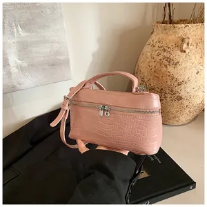 Detail of pink crocodile embossed bag showing top handle and silver zippers in scene.