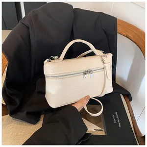Elegant cream-colored box bag with crocodile skin texture and silver zipper details