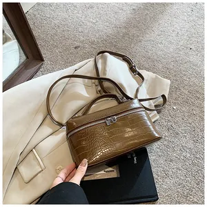 Detailed view of a brown crocodile texture box handbag placed on a beige coat background