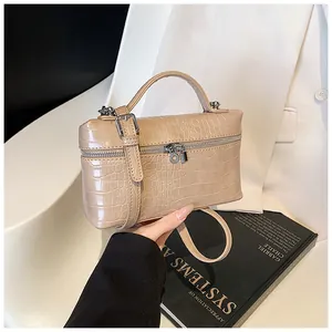 Detail view of beige crocodile embossed box handbag with metal zipper and top handle