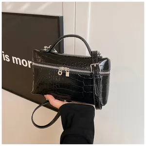 Detail view of a black crocodile texture box bag with silver zipper and handle.
