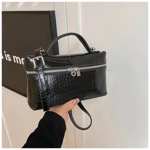 Close-up of a stylish black crocodile-patterned box handbag with silver hardware
