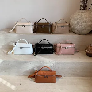 Elegant crocodile-patterned mini box bags in multiple colors displayed on minimalist stone steps