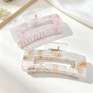 Detail view of two elegant acrylic hair claw clips with sweet floral patterns in soft colors