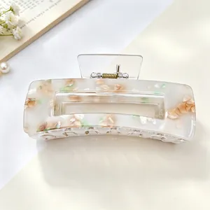 Close-up detail of a cream acrylic rectangle hair claw clip with floral patch patterns