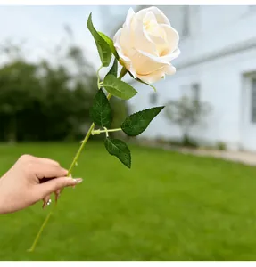 Detailed view of realistic cream artificial rose with delicate silk petals and green leaves