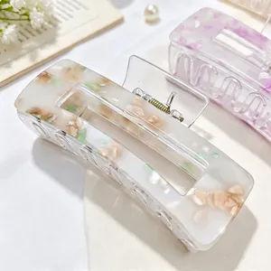 Close-up detail of a square acrylic claw clip with cream and floral shell patterns