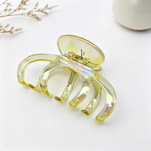 Gros plan d'une grande pince à cheveux citrouille jaune irisée au fini transparent.