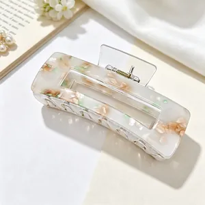 Detailed close-up of a floral acrylic rectangular hair claw clip in soft lighting