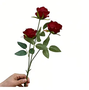 Detalle de una rosa artificial de tres cabezas rojo oscuro sostenida para ver el tamaño