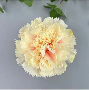 Detailed top-down view of a light yellow artificial carnation flower head with pink center.