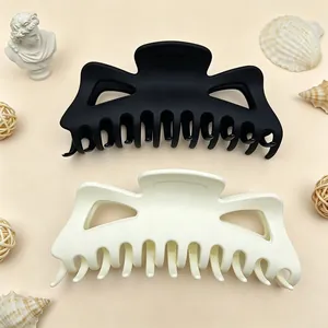 Detail view of large matte finish hair claw clips in black and cream colors for thick hair