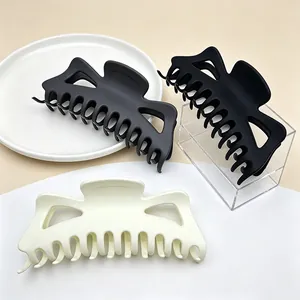 Detail of large matte hair claw clips in black and cream colors shown with elegant props