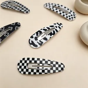 Set of black and white patterned waterdrop BB hair clips on a clean beige surface