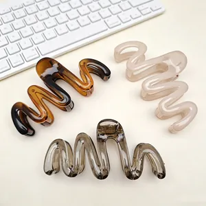 Detailed view of three colorful wavy PC hair claw clips on a clean desk background.