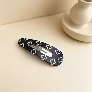 Detailed macro view of a UV printed black and white waterdrop BB hair clip with clover patterns