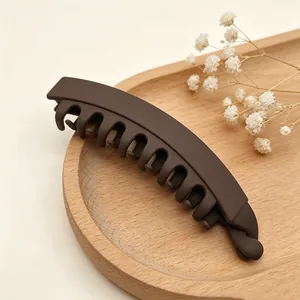 Λεπτομερής προβολή μεγάλου κλιπ μαλλιών μπανάνας 13cm σε ματ καφέ χρώμα σε ξύλινο δίσκο
