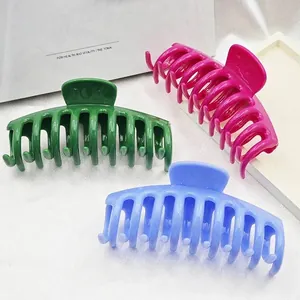 Detail of three large hair claw clips in vibrant green, fuchsia, and blue colors