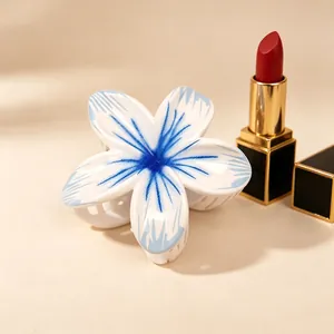 Detail of blue and white frangipani hair claw clip with glossy finish