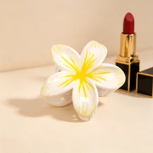 Close-up detail shot of the white and yellow plumeria flower hair claw clip design.