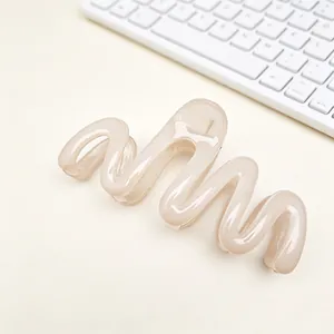 Close-up detail showing the wavy design of a beige PC material hair claw clip on a desk