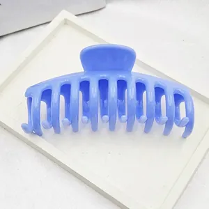 Macro view of large blue plastic hair claw clip displayed on a minimalist white tray