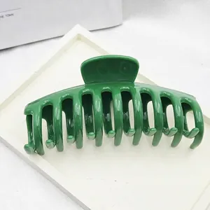 Detail shot of a glossy dark green dragon bone hair claw clip displayed on a white tray.