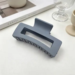 Gros plan d'une pince à cheveux carrée gris mat posée sur une surface minimaliste