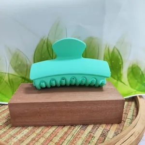 Macro view of a matte mint green rectangular hair claw clip on a wooden block
