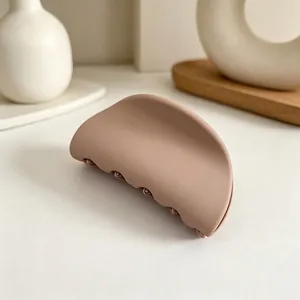 Nahaufnahme einer mattbeigen halbrunden Haarklammer auf einem schlichten Hintergrund.