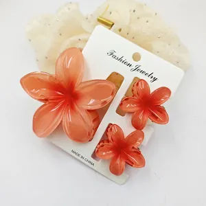 Three-piece set of translucent orange plumeria flower hair clips on display card.