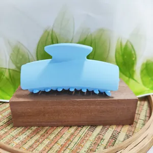 Detailed view of a light blue rectangular hair claw clip on a wooden display base