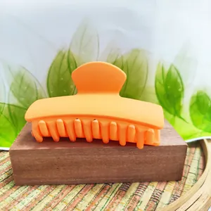 Detailed view of an orange matte rectangle hair claw clip on a wooden stand