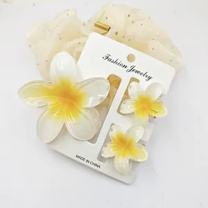Detailed view of sweet plumeria flower hair clip set on a white display card for summer