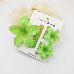 Detailed view of three green frangipani flower hair claw clips on a white card