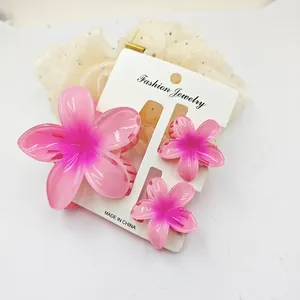 Close-up of three pink plumeria flower hair claw clips in a summer resort jewelry set