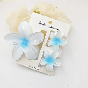 Close-up detail of blue gradient frangipani flower hair claw clip set for summer vacation