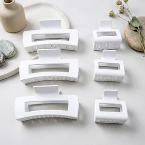 Close-up detail of matte white square hair claw clips in large and medium sizes