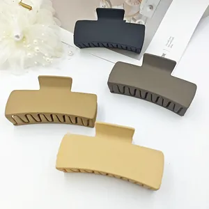 Detail showing four matte rectangular hair claw clips in black and neutral solid colors