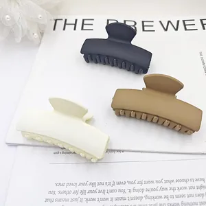 Set of three matte rectangular hair claw clips in black, brown and cream white colors.