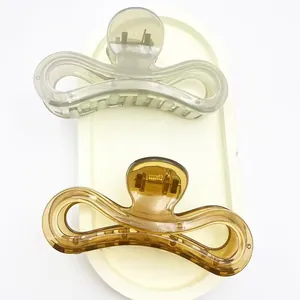 Detail view of two jelly-colored hair claw clips in amber and grey on a cream tray.