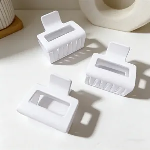Close-up of three white matte square hair claw clips on a minimalist background