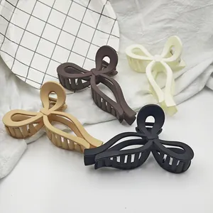 Macro detail view of four matte bow-shaped hair claw clips on white textured fabric