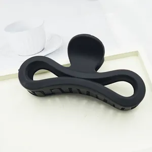 Detailed view of a large matte black bow-shaped hair claw clip placed on a white tray