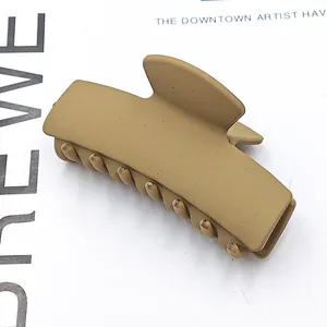 Close-up of a matte olive green rectangular hair claw clip on a minimalist background