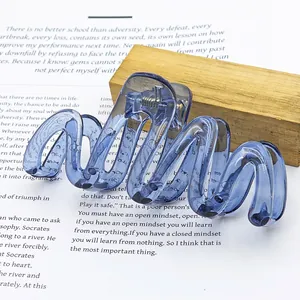 Macro detail of large wave-shaped hair claw clip in a translucent jelly blue finish