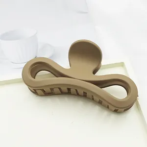 Close-up of a large matte khaki hair claw clip featuring a unique bow-shaped design.
